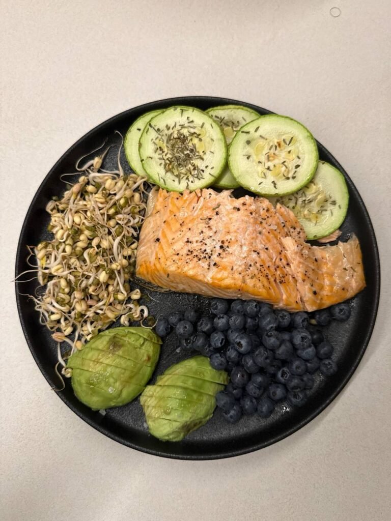 Plato con salmón, aguacate, arándanos, pepino y brotes.
