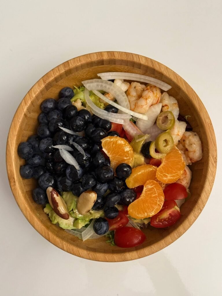 Ensalada con gambas, mandarina, arándanos y verduras en un bol.