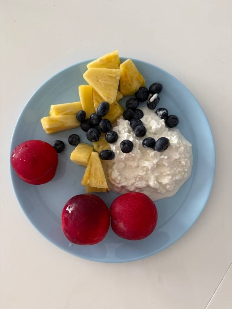 Plato con piña, arándanos, requesón y ciruelas.