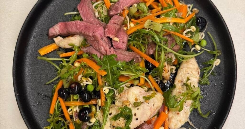 Plato de ensalada con pollo, ternera, zanahoria y arándanos
