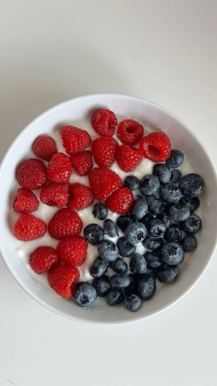 Bol de yogur con frambuesas y arándanos frescos.