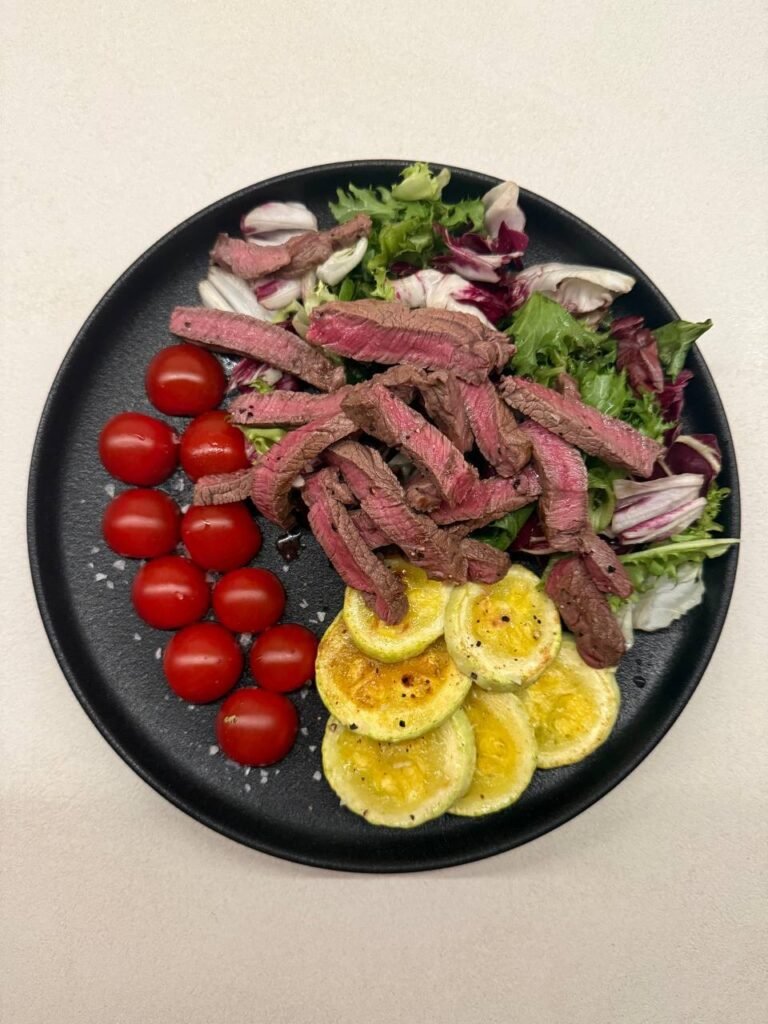 Plato con ensalada de lechuga, ternera, tomates cherry y calabacín.