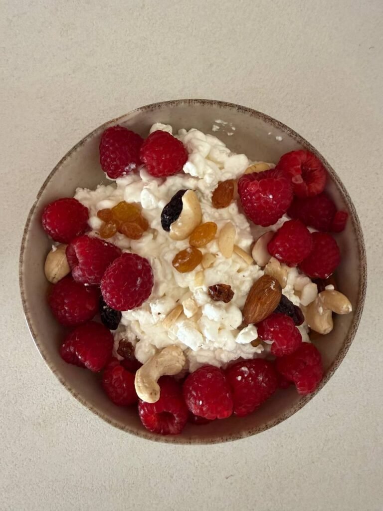 Tazón con requesón, frambuesas y frutos secos.