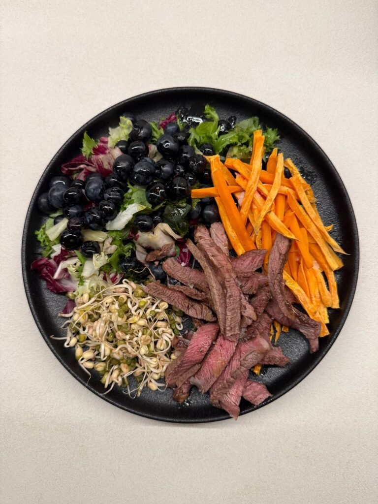 Plato de ensalada con ternera, arándanos, brotes y zanahorias.
