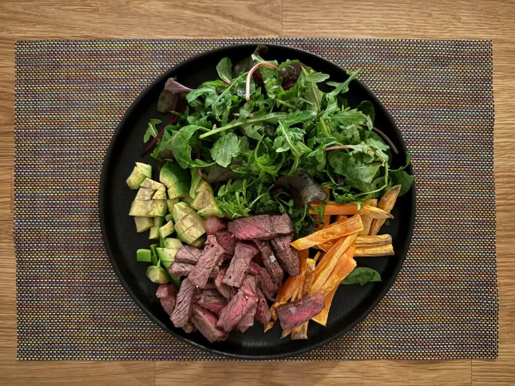 Plato con ensalada, ternera, aguacate y boniato.